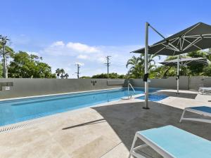 a swimming pool with an umbrella and a table and chairs at Unit 3 Taralla 18 Edgar Bennett Avenue Noosa Heads in Noosa Heads