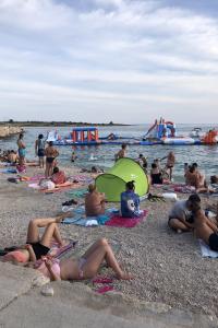a group of people sitting on the beach at Apartments by the sea Novalja, Pag - 13033 in Novalja