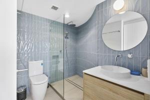 Un baño con inodoro, lavabo y espejo. en Unit 5 Vista Pacific 12 14 Bryan Street Sunshine Beach, en Sunshine Beach 7 fotos más