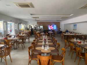 a dining room with tables and chairs and a tv at Reserva do Sahy-Mangaratiba Condado Loft Sol & Sal in Mangaratiba