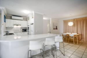 a kitchen with white cabinets and a table and chairs at Unit 4 Cote DAzur 6 Douglas Street Sunshine Beach in Sunshine Beach
