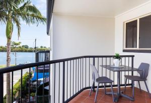 balcón con mesa, sillas y vistas al agua en River Sands Apartments, en Maroochydore