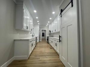 Una gran cocina blanca con armarios blancos y suelo de madera. en Peaceful Sears, Roebuck and Company Mail Order Home., en Henderson