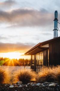 a building with the sunset in the background at Peak View Cabin - Ben Ohau - Stylish Seclusion in Twizel