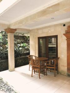 a porch with a wooden table and two chairs at Darma Yogi House in Ubud