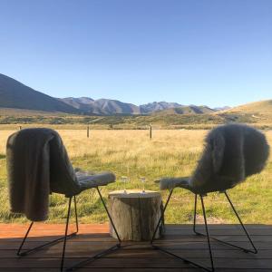 two chairs sitting next to a table with wine glasses at Peak View Cabin - Ben Ohau - Stylish Seclusion in Twizel