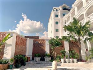 a large white building with palm trees in front of it at Thuận Phát Hotel in Soc Trang +53 photos
