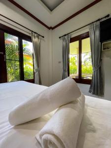 a bedroom with a bed with white sheets and windows at Mingmongkol Resort in Koh Samui 