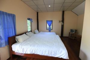 a bedroom with a large white bed with blue curtains at banrainaifun 