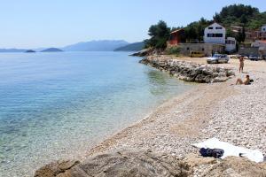 a group of people sitting on a beach next to the water at Apartments with a parking space Savar, Dugi otok - 14373 in Savar