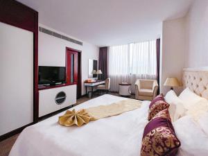a hotel room with a large bed and a television at Sapaly Lao Cai City Hotel in Lao Cai
