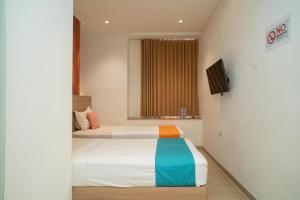 a bedroom with two beds and a television in it at Sans Hotel Kupang Indah Surabaya by RedDoorz in Kupang