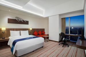 ジャカルタにあるホリデイ イン エクスプレス ジャカルタ プルイト シティゲートのベッド、デスク、テレビが備わるホテルルームです。