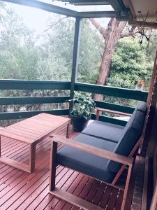 a wooden deck with a bench and a table at Gorgeous house near beach with nature view in Frankston