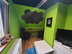 Zimmer mit einer grünen Wand, einem Schreibtisch und einem Tisch in der Unterkunft Eden nad Lubie Linowno 