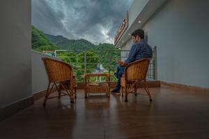 un hombre sentado en una silla mirando por la ventana en Hotel Rishikesh Grand by Kool-Stays, en Rishīkesh