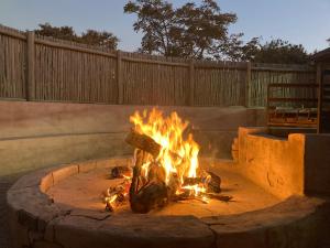 un fuego arde en un foso de fuego en un patio en Moletani Game Ranch, en Kareefontein