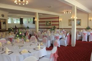 un salón de banquetes con mesas blancas y sillas rosas en Beambridge Inn, en Wellington