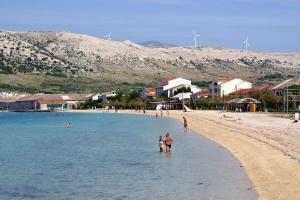 a group of people standing in the water on a beach at Apartment Pag 16100c in Pag