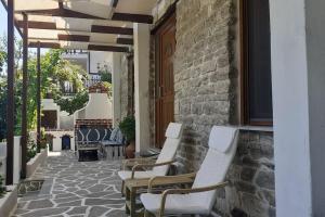 a patio with white chairs and a stone floor at Relax Holistic House in Potamia