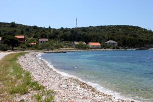 a rocky beach with houses in the background at Apartments and rooms by the sea Cove Soline, Dugi otok - 448 in Veli Rat