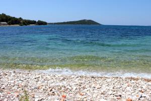 a rocky beach with the water and an island at Apartments and rooms by the sea Cove Soline, Dugi otok - 448 in Veli Rat
