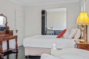 um quarto branco com uma cama e uma televisão em Old Fernshaw Cottage em Healesville