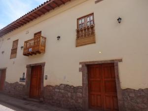 a white building with wooden doors and windows at OkiDoki Cusco Hostal in Cusco