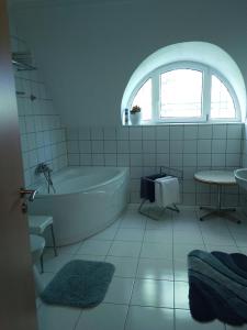 a white bathroom with a tub and a window at Castelinho Apartmanház in Gyenesdiás