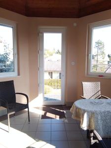 a room with two windows and a table and chairs at Castelinho Apartmanház in Gyenesdiás
