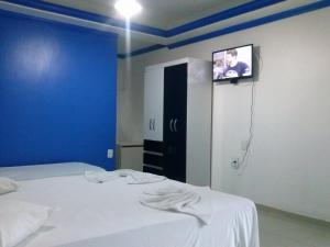 a bedroom with a bed with a tv on the wall at Hotel Lagoa Azul in Porto Seguro