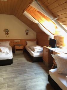 a room with two beds and a desk with a television at Alte Rose Gasthaus in Ebelsbach