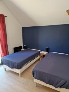 1 dormitorio con 2 camas y pared azul en Villa Nomy, en Grandes Sables
