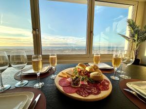 een tafel met een bord eten en wijnglazen bij Le Haut de Gamme Vue mer - Malo cation in Duinkerke