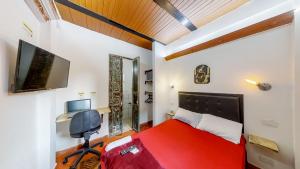 Casa Los Naranjos Hostal في ميديلين: غرفة نوم بسرير احمر وتلفزيون بشاشة مسطحة