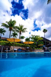 a swimming pool with yellow umbrellas and palm trees at Fisherman's Cove Resort in Bel Ombre