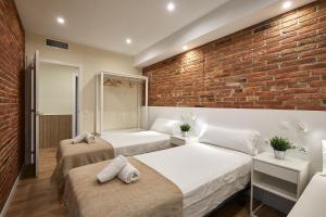 a bedroom with two beds and a brick wall at BBarcelona Sagrada Familia Flats in Barcelona