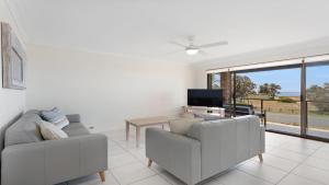 a living room with two couches and a television at Surfspray 4 Pebbly Beach in Forster