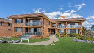 a brick house with a lawn in front of it at Surfspray 4 Pebbly Beach in Forster