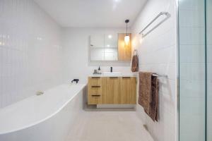 Baño blanco con bañera y lavamanos en SEASIDE ESCAPE@ The Cosmopolitan Unit 10406, en Maroochydore