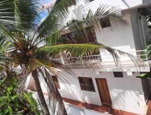a white house with a palm tree in front of it at VARMA SEA VIEW VILLAS in Trivandrum