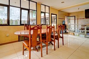 a dining room with a wooden table and chairs at OYO 91547 Graha Hermawan Guest House Syariah in Bandung