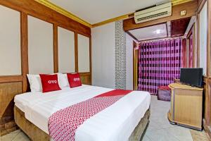 a bedroom with a bed with red pillows and a tv at OYO 91525 Hotel Bugisan in Ngabean