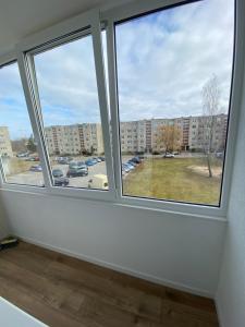an empty room with three windows and a parking lot at ETG Apartment in Mažeikiai