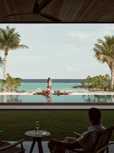 a man sitting in a chair in front of a window at Patina Maldives, Fari Islands in North Male Atoll