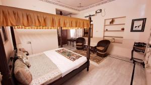 1 dormitorio con 1 cama con dosel y 2 sillas en Sun Heritage Home, en Udaipur