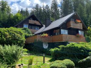 a large wooden house with balconies and trees at Chata Jezevec in Hojsova Stráž