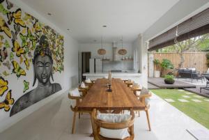 una sala da pranzo con un grande tavolo in legno e sedie di Mahasari Villa a Seminyak