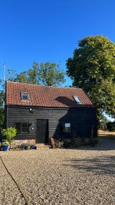 a large black barn with a red roof at Gorgeous comfortable barn with huge private orchard in quiet Suffolk location in Depden