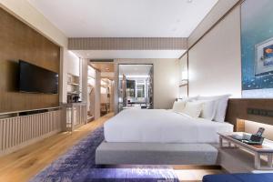 a bedroom with a large white bed and a flat screen tv at The Anandi Hotel and SPA - Luxury Healing Hotel for Wellbeing in Shanghai